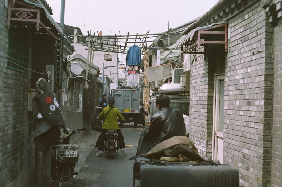 People walking down a narrow hutong alleyway in Beijing's Xicheng District
