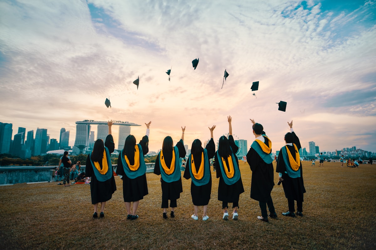 Chinese graduates in caps and gowns throwing their hats in the air — celebrating graduation season in China