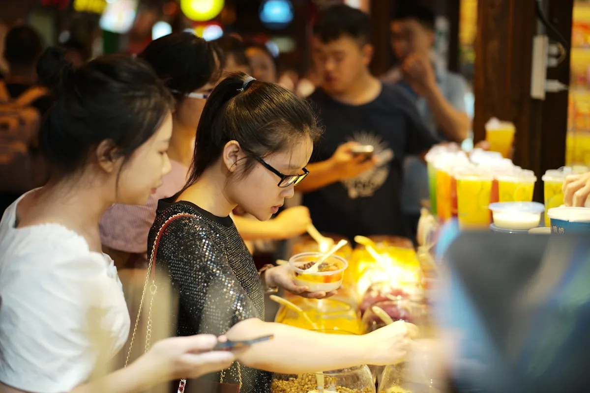 People choosing food at a busy night market stall in Chongqing