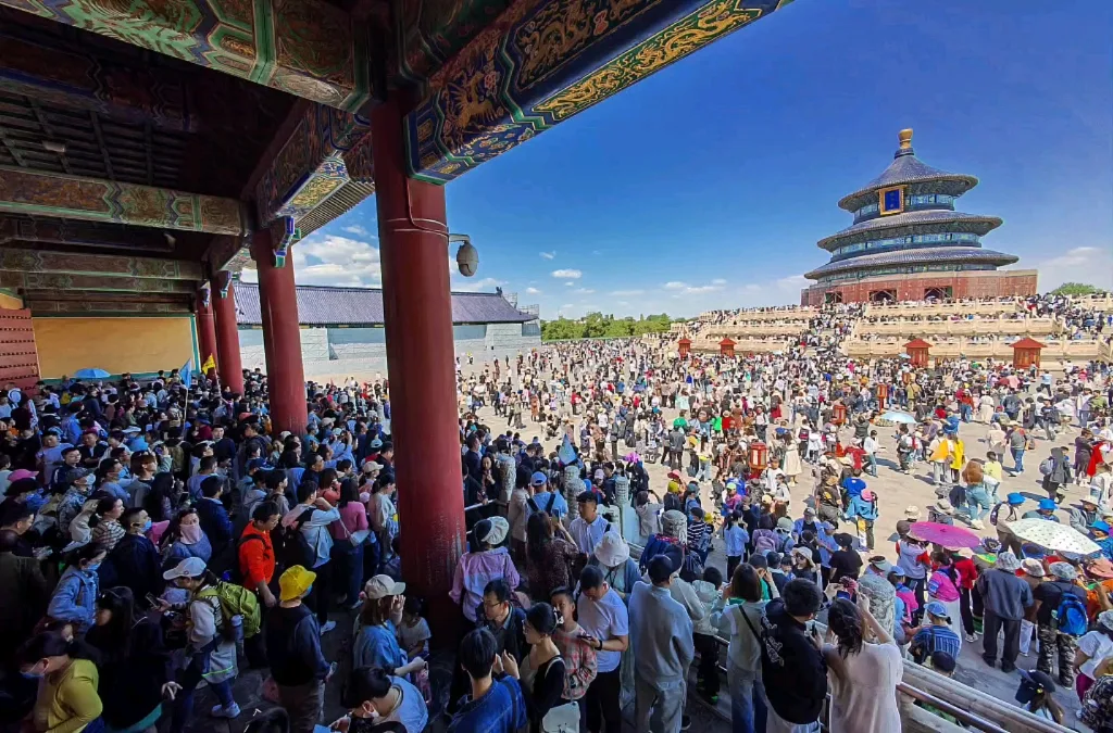Multidão reunida em frente a um grande edifício tradicional chinês durante a Golden Week