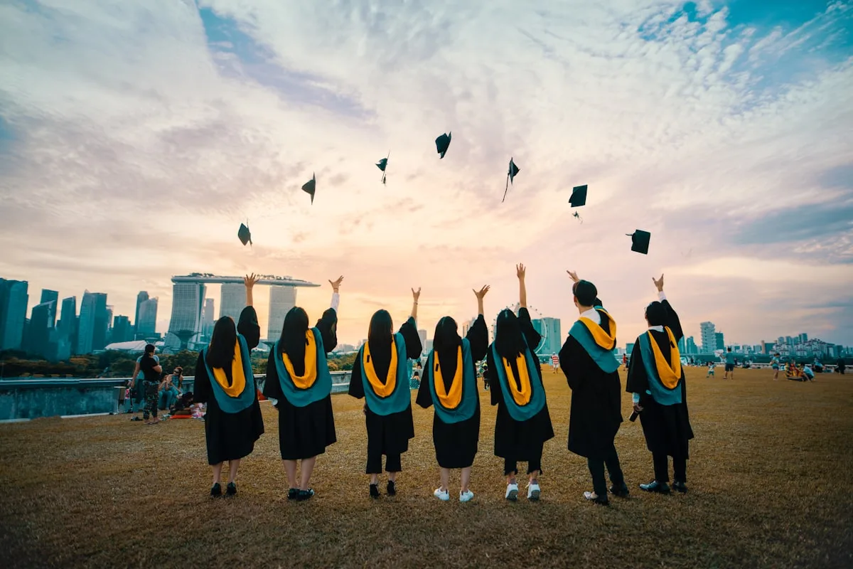 Graduates in caps and gowns throwing their hats in the air, celebrating graduation season