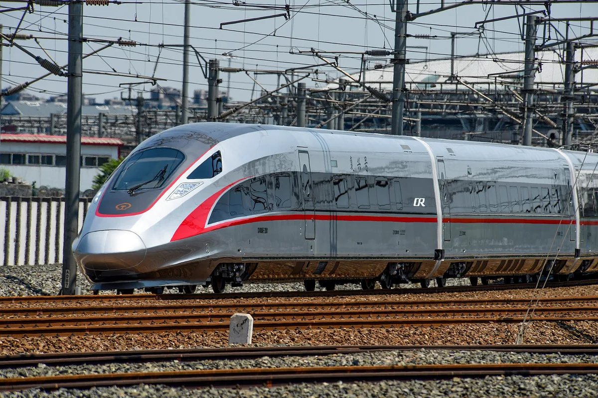 Um trem de alta velocidade CR400AF Fuxing em pintura prateada e vermelha cruzando um feixe de vias perto de Pequim (Photo: N509FZ via Wikimedia Commons)