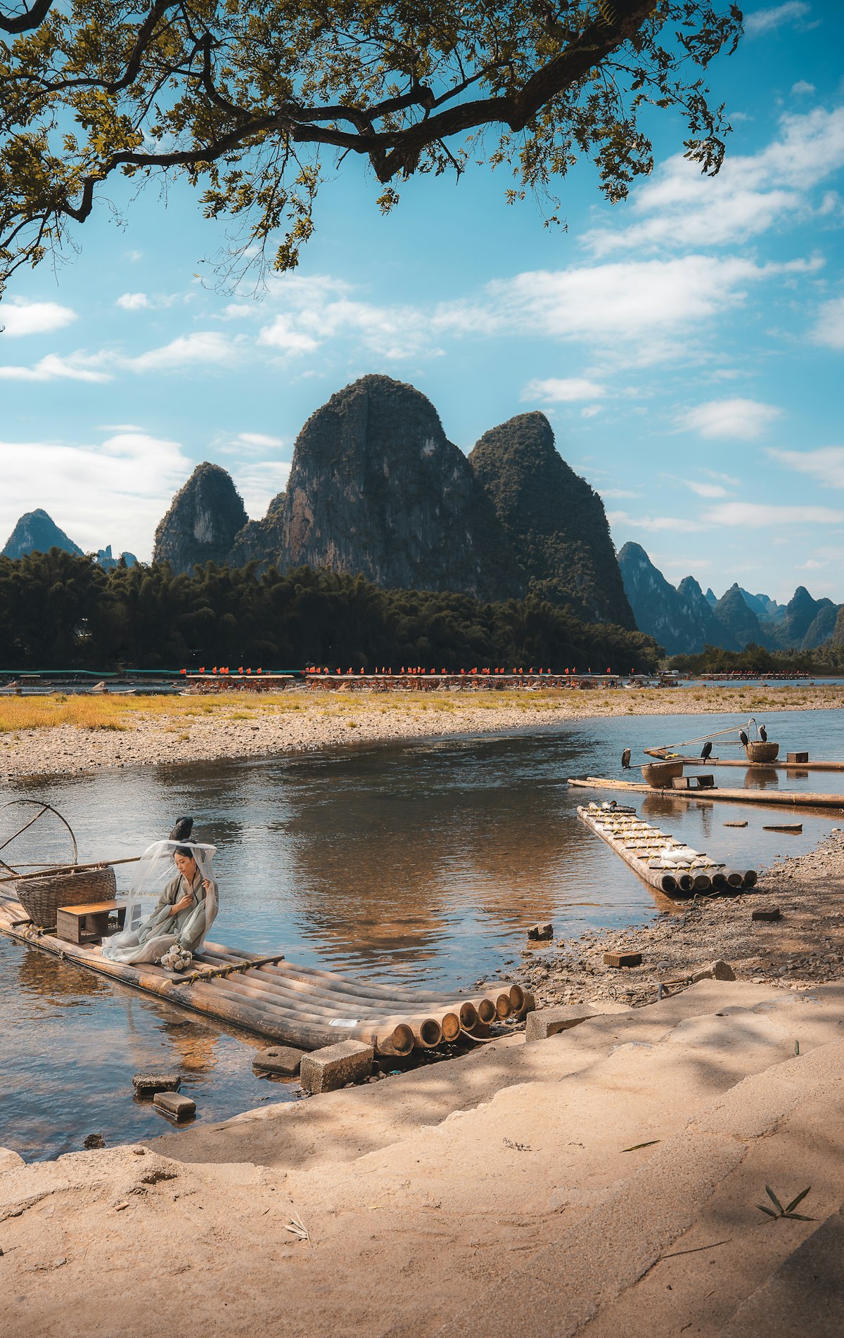 Sunset at Gongnong Bridge — bamboo rafts glide through golden light as karst peaks silhouette against the evening sky