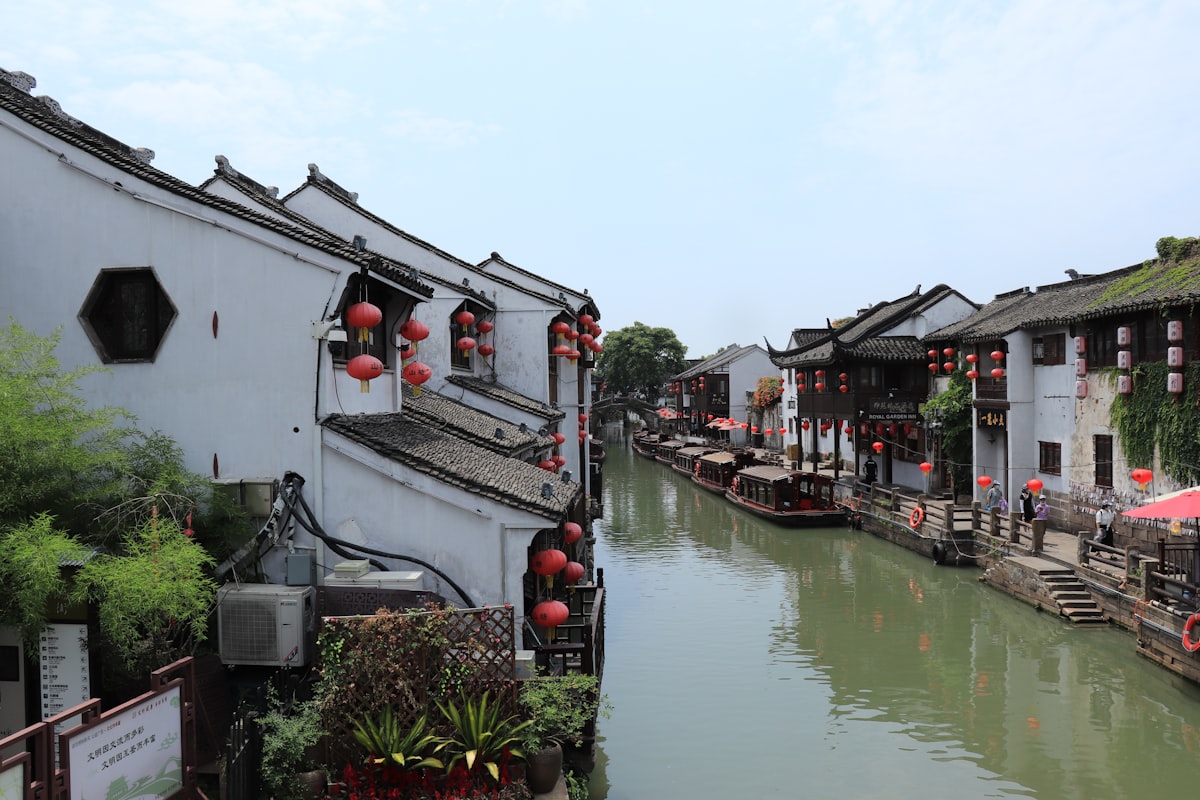 White and red boat floating on a peaceful canal in Suzhou's ancient water town
