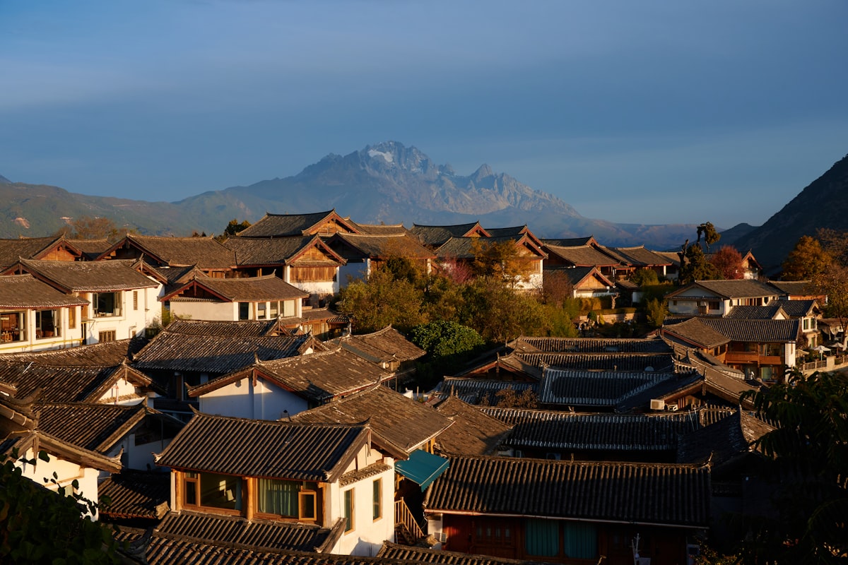 Traditional village rooftops with mountain backdrop at sunrise in Lijiang, Yunnan