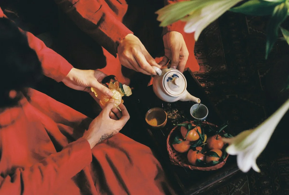 Deux personnes en tenue traditionnelle rouge servant le thé à une table de cérémonie du thé