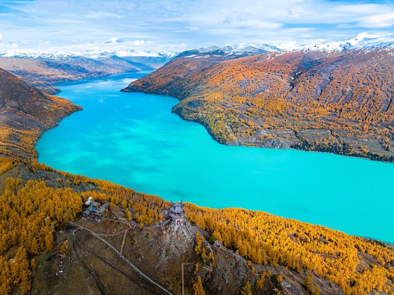 Kanas Lake in Xinjiang — turquoise water surrounded by forest and snow-capped mountains