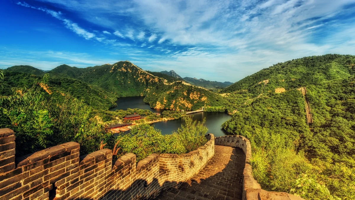 The Great Wall meeting the water at Huanghuacheng, the wall snaking along a wooded ridge and into the lake