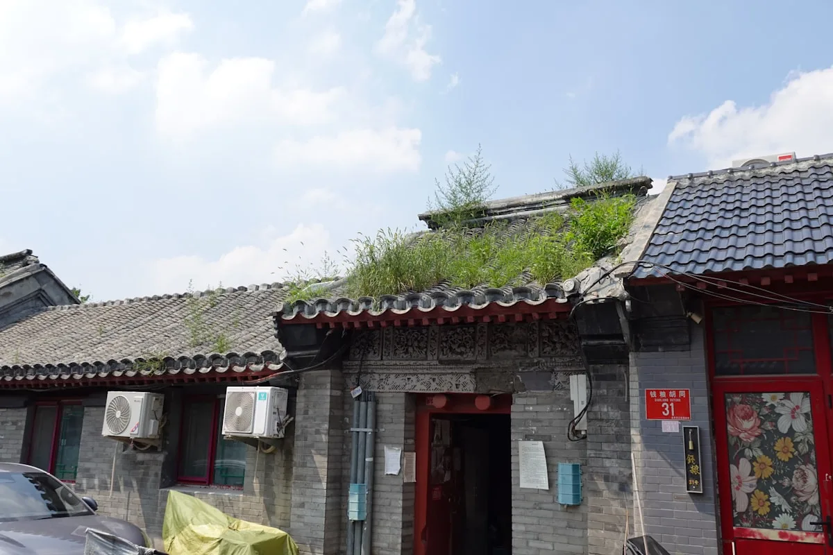 A grey-brick siheyuan courtyard gatehouse in a Beijing hutong, the traditional courtyard houses where many boutique guesthouses are based