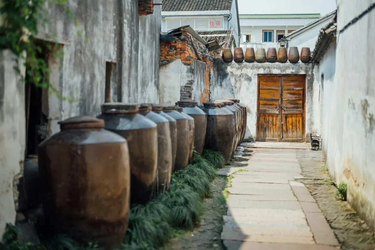 Des rangées de jarres de vin en céramique le long d'une ruelle aux murs blanchis à Shaoxing