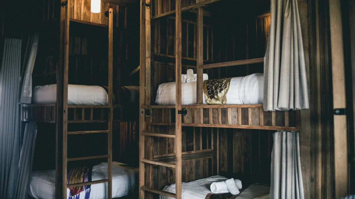 Wooden bunk beds with privacy curtains and patterned fabric in a hostel dorm room