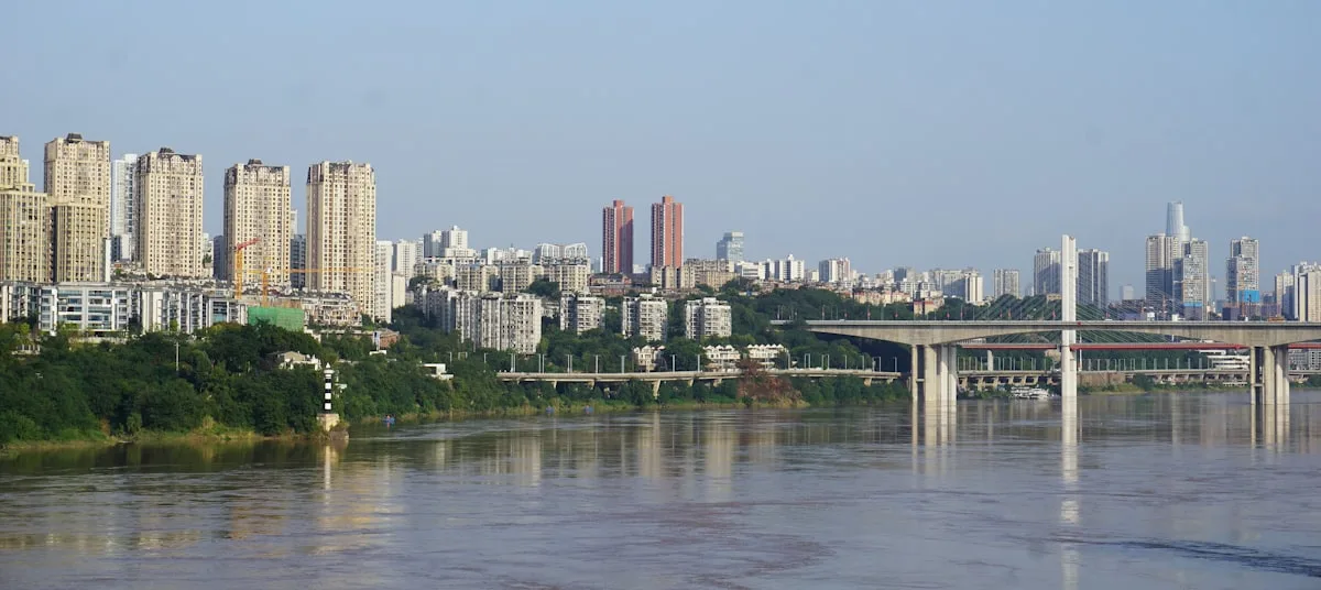 Chongqing's riverside skyline at night with a bridge across the river and the city lights reflected in the water