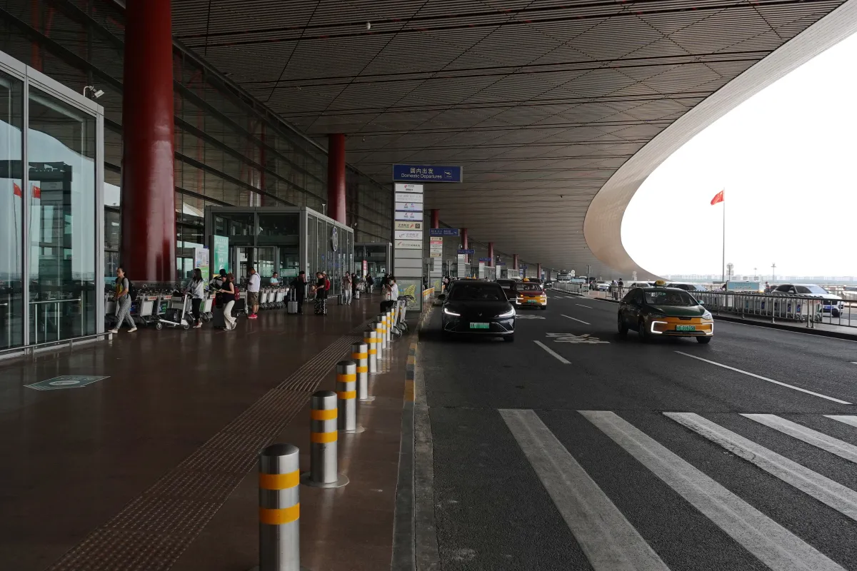 Departure curbside at Beijing Capital International Airport Terminal 3 with taxis and luggage carts (Photo: 颐园居 via Wikimedia Commons)