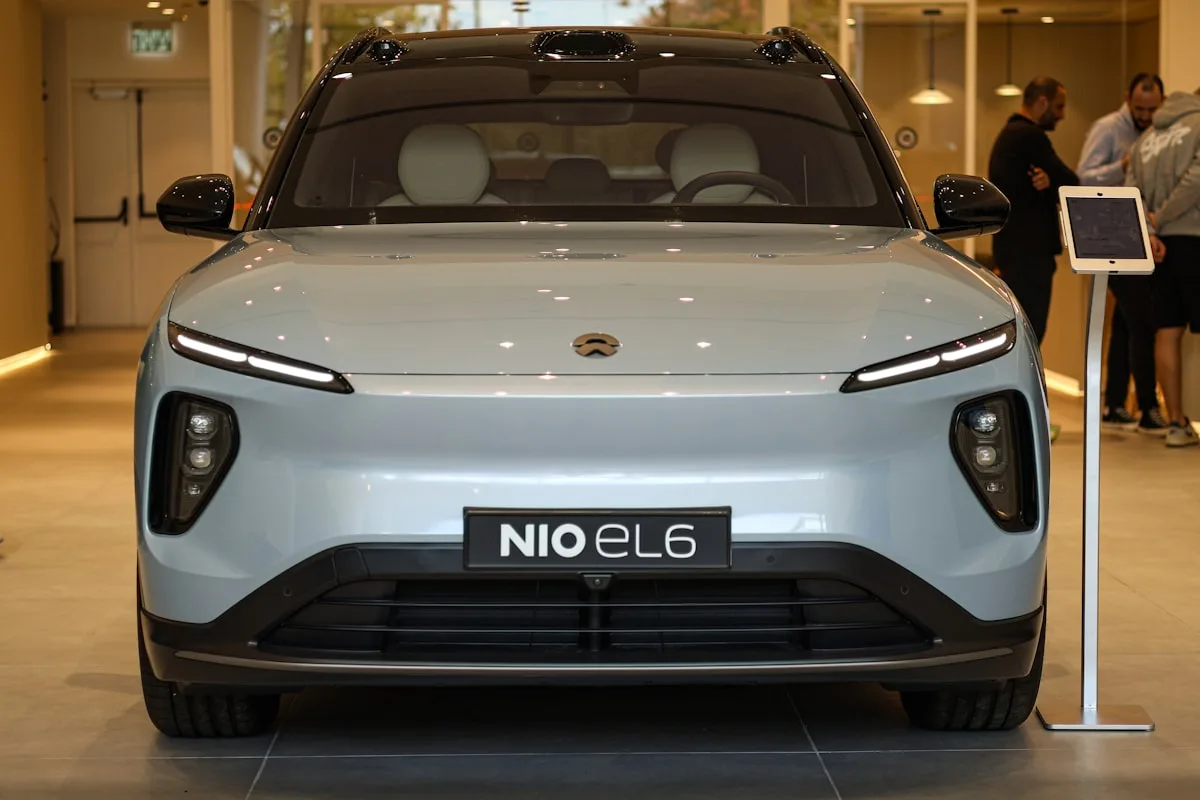 Visitors look at a light blue NIO electric SUV displayed in an indoor showroom