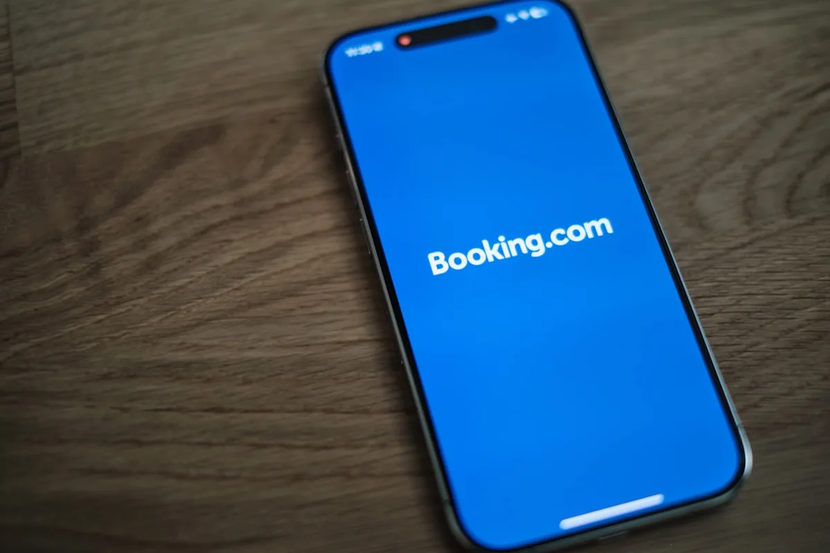 A smartphone showing the Booking.com app resting on a wooden table