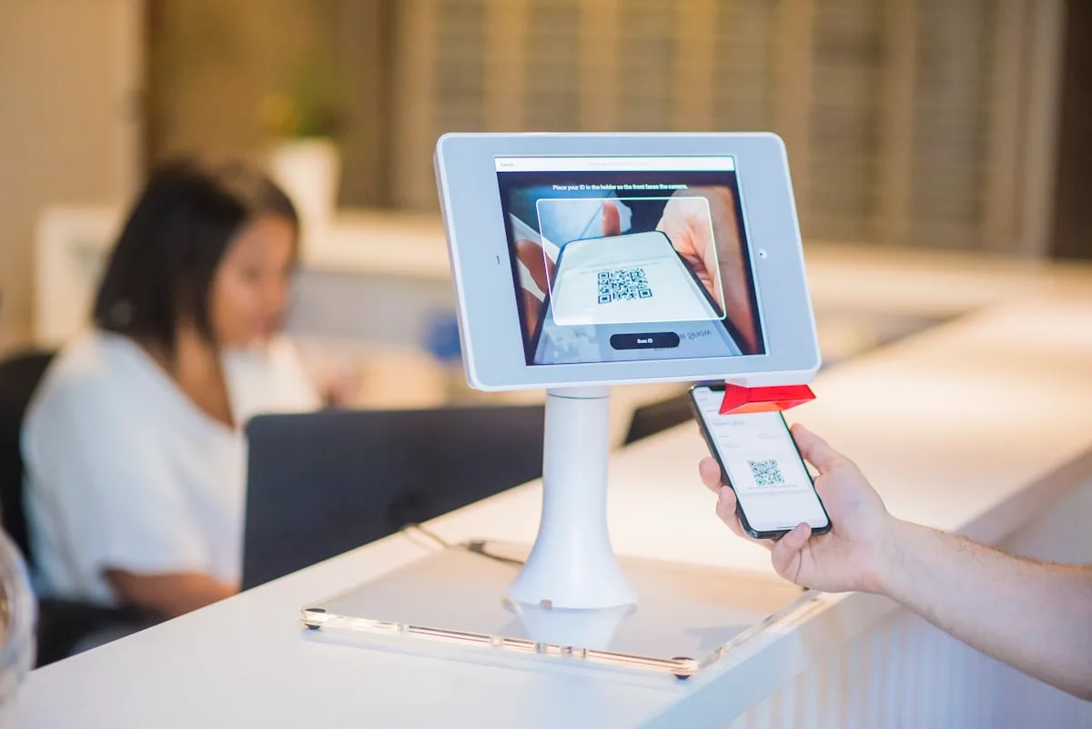 Traveler scanning a QR code on a tablet at a hotel reception desk to check in
