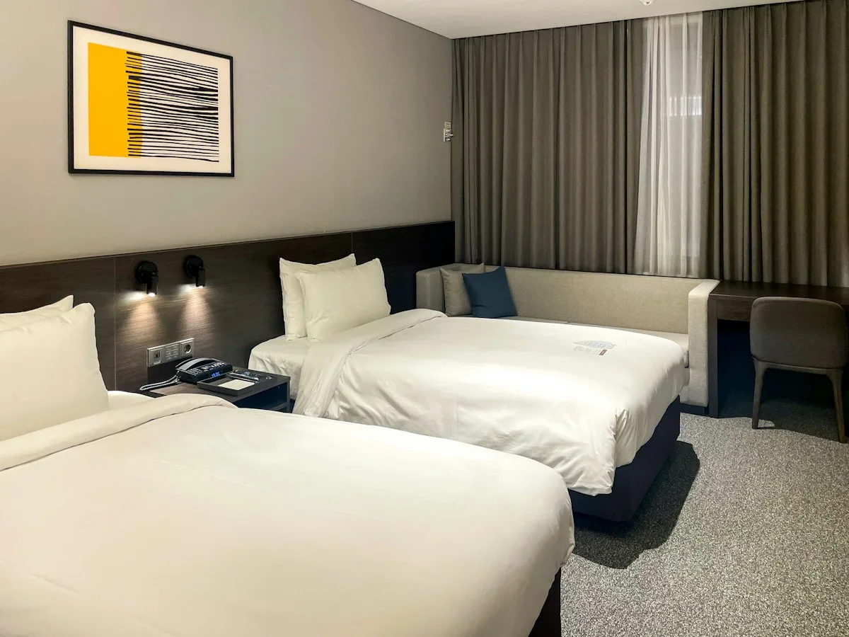 Um quarto de hotel simples com duas camas e cabeceiras de madeira