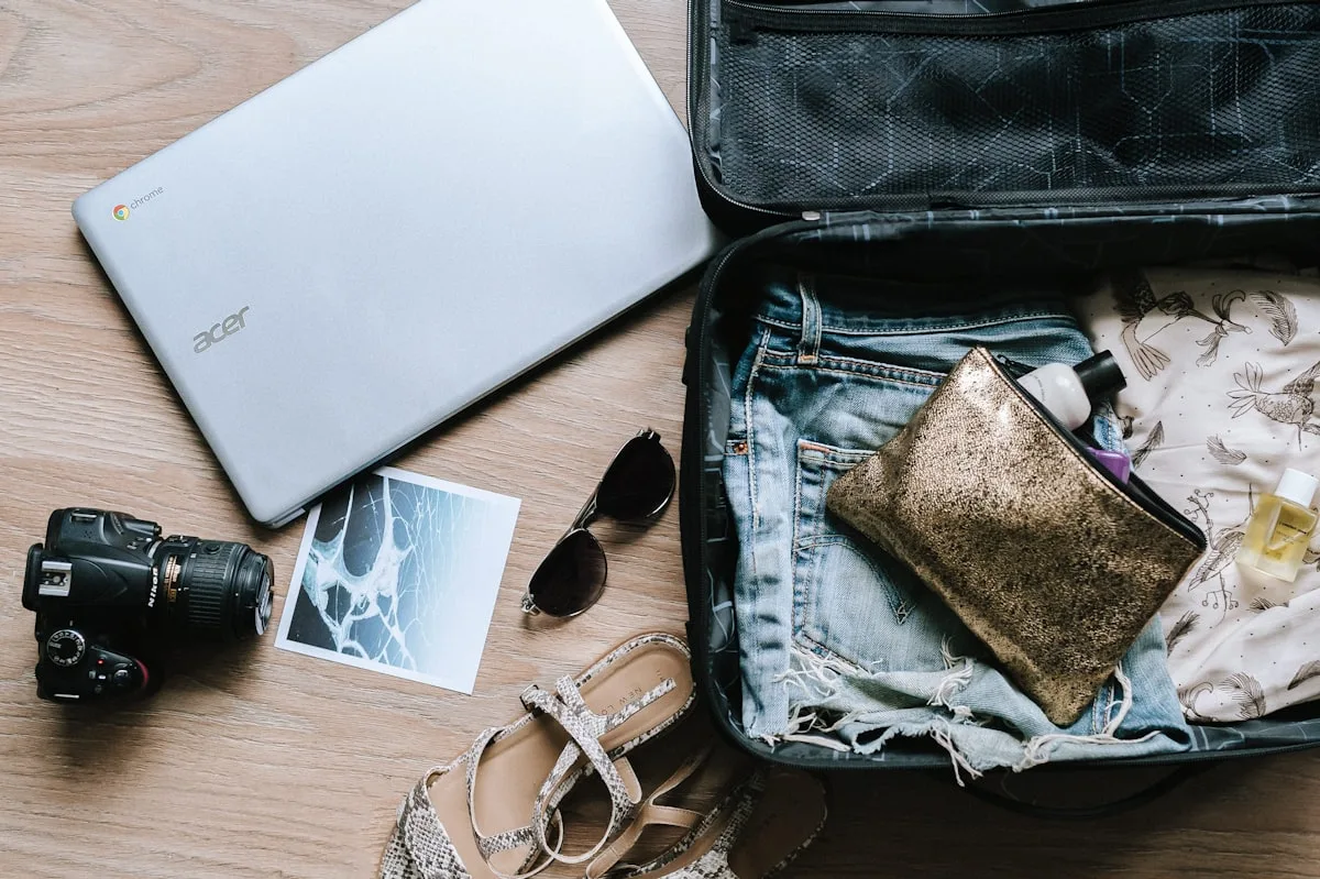 A flat-lay of packing for a China trip: an open suitcase with clothes, a laptop, a camera and sunglasses