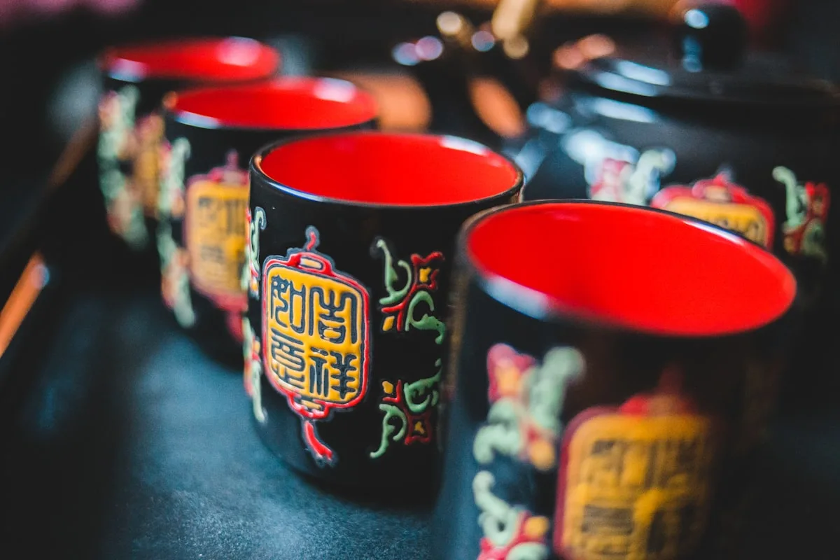 A set of black Chinese lacquer tea cups with red interiors and auspicious patterns
