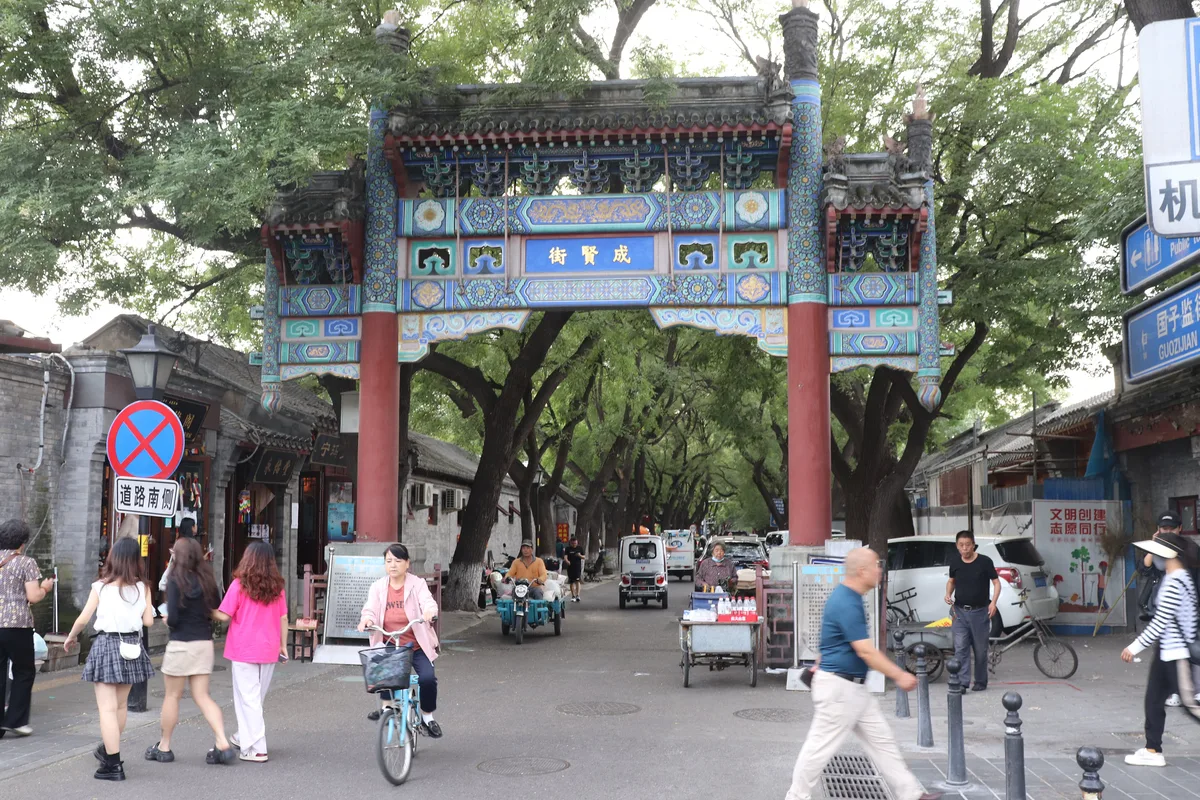 O arco paifang pintado na entrada da Guozijian Street, em Pequim, com ciclistas e pedestres passando por baixo (Photo: Andrzej Otrębski via Wikimedia Commons)