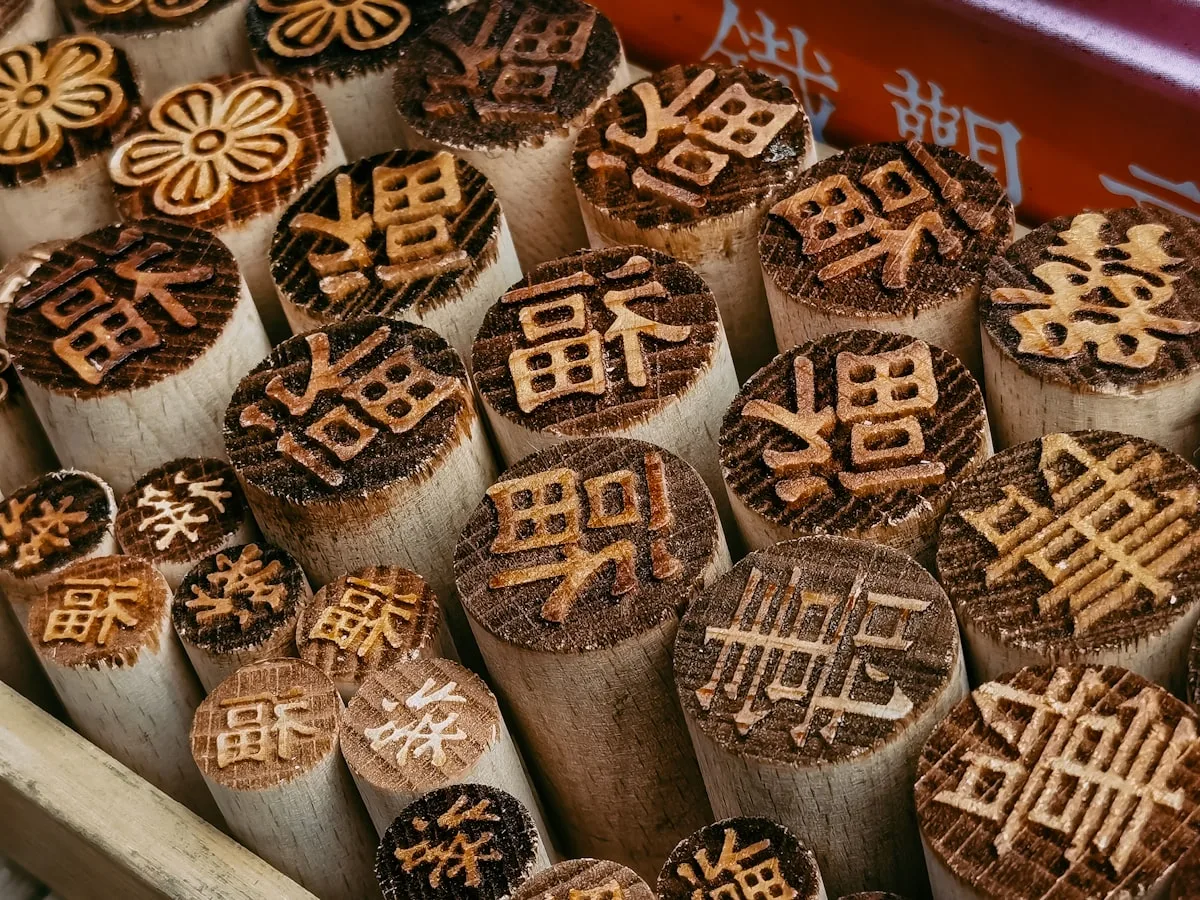 A box of carved Chinese wooden name seals — single characters like 福 (fortune) and 喜 (joy), each one a compact word with its own meaning
