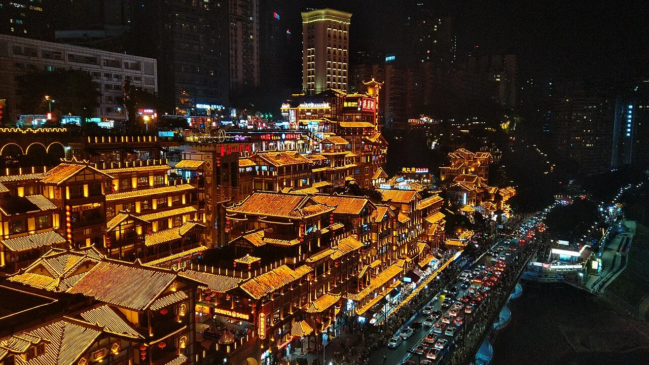 Hongyadong's tiered stilt-house complex glowing at night, seen from Qiansimen Bridge across the Jialing River (Photo: Jonashtand via Wikimedia Commons)