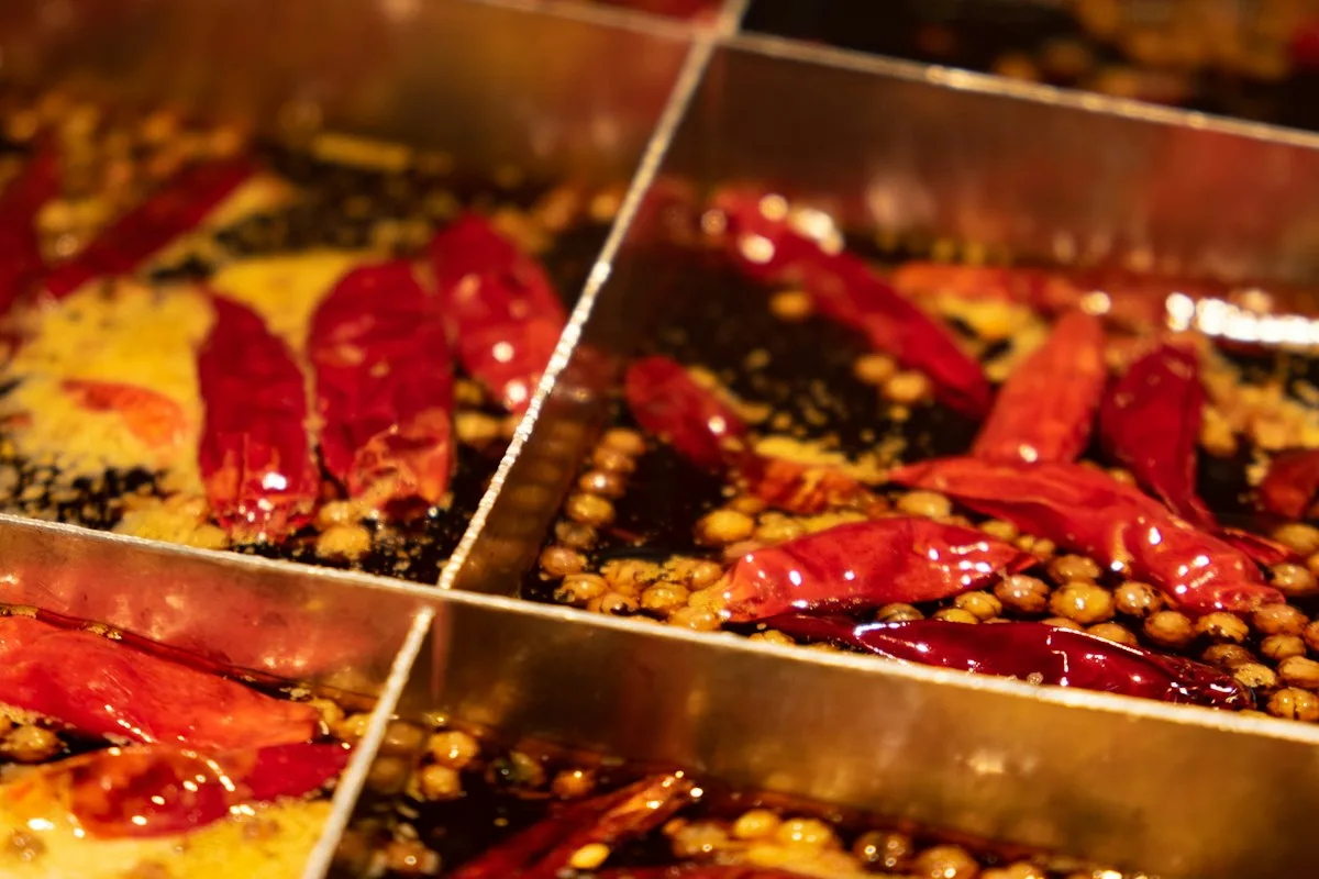 A bubbling nine-grid Chongqing hot pot, red chili oil shimmering with dried chilies and Sichuan peppercorns