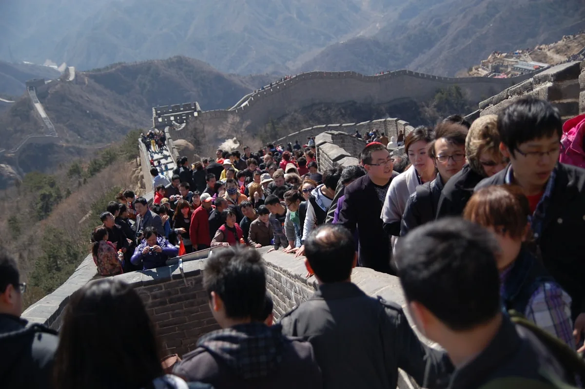 A dense line of tourists walking along the Great Wall, the crowd filling the wall between watchtowers