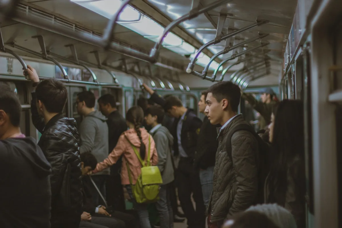 Commuters packed into a Chinese subway car, passengers standing close together holding the overhead rails