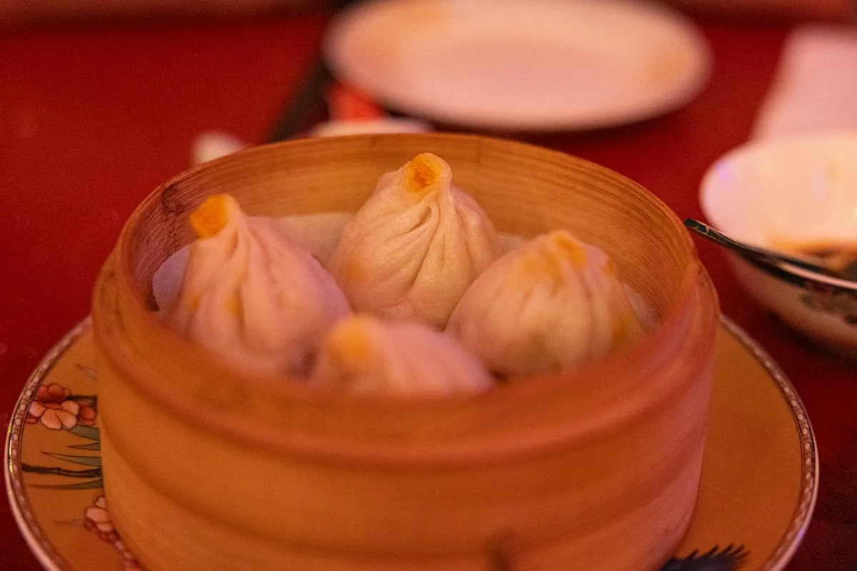 Soup dumplings in a bamboo steamer on a restaurant table