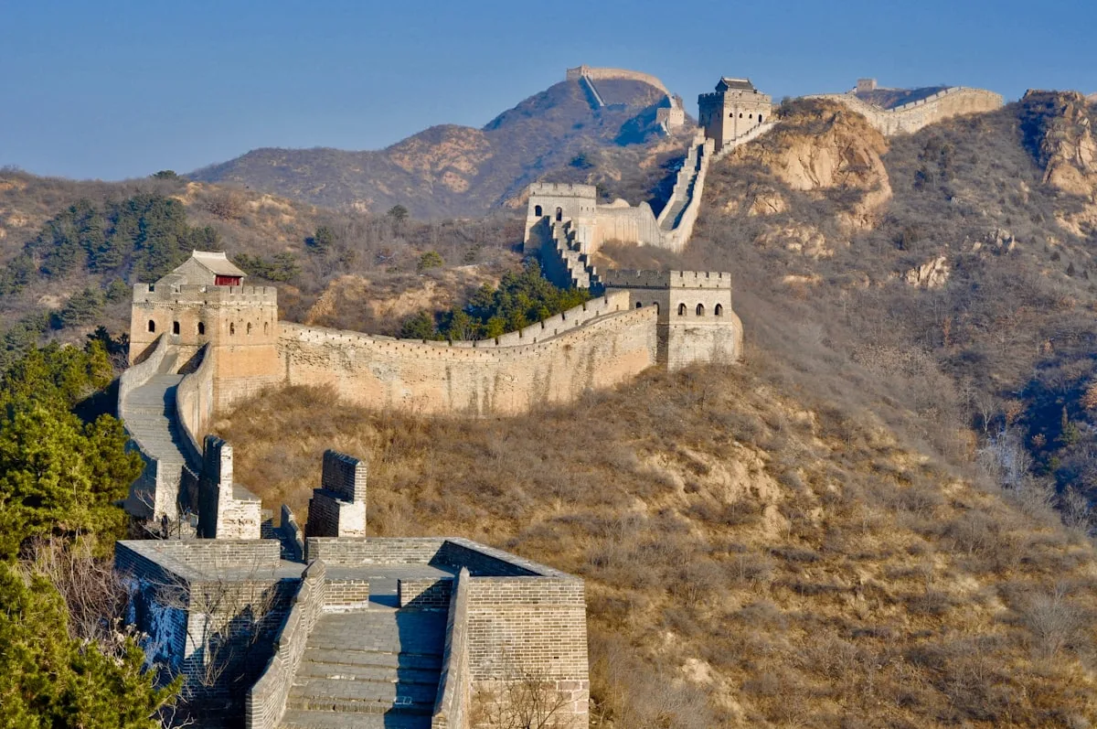 La Grande Muraille de Jinshanling au lever du soleil — la muraille serpente le long des crêtes montagneuses avec 67 tours de guet, la plus forte concentration de toutes les sections.