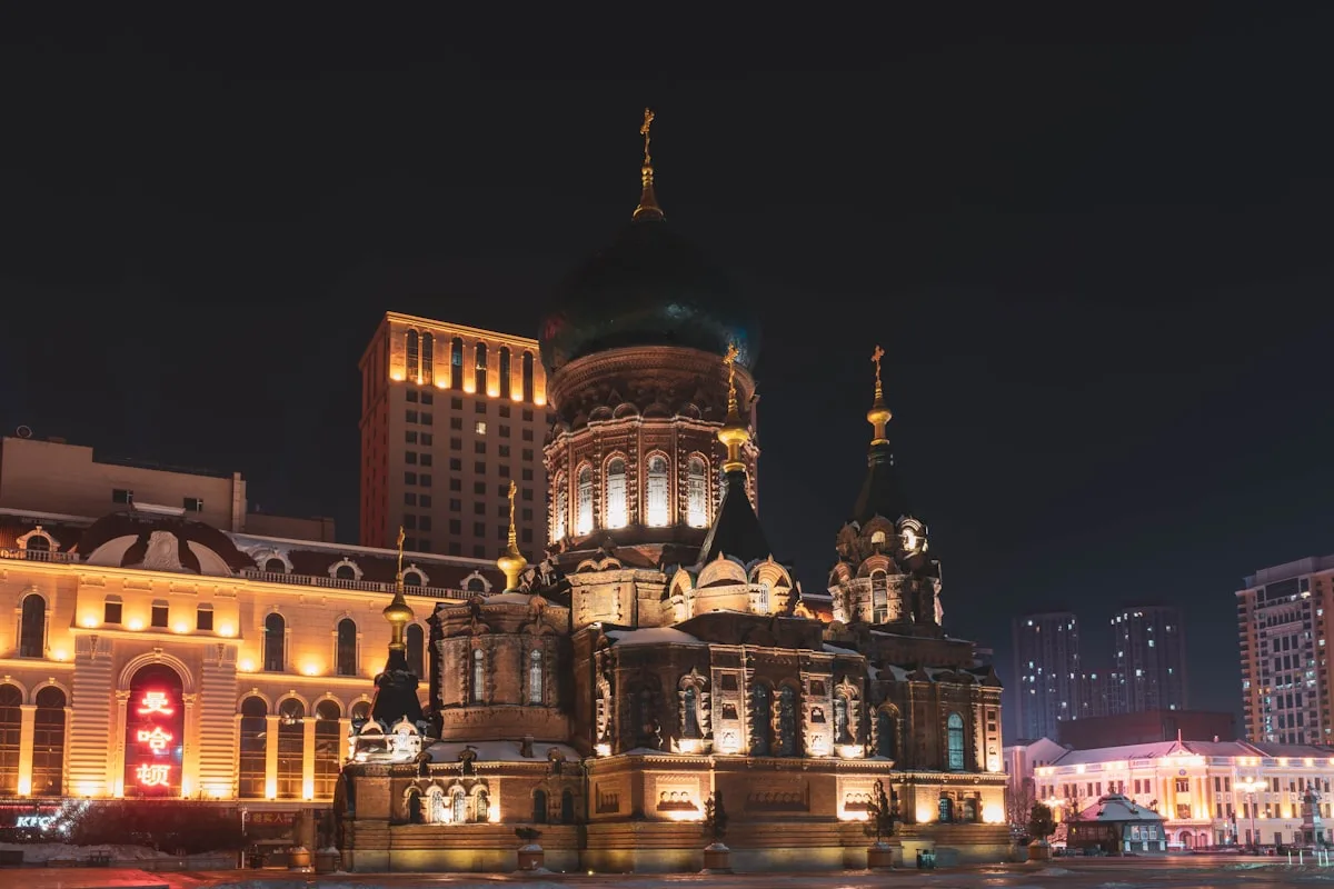 Harbin's St. Sophia Cathedral glowing under floodlights at night with snow-covered ground around it