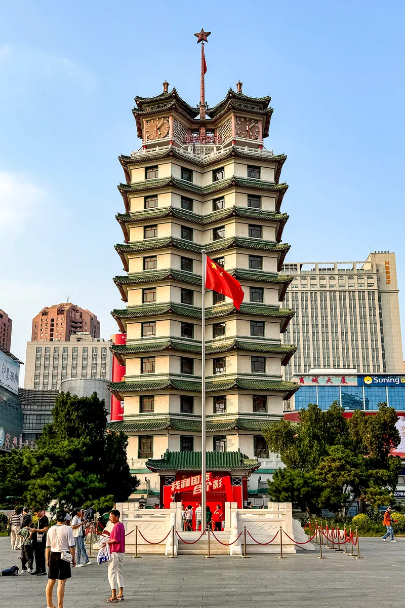 La tour commémorative Erqi au centre de Zhengzhou, tour à étages aux toits de tuiles vertes, au-dessus d'une place et d'une ligne d'immeubles modernes (Photo: Windmemories via Wikimedia Commons)