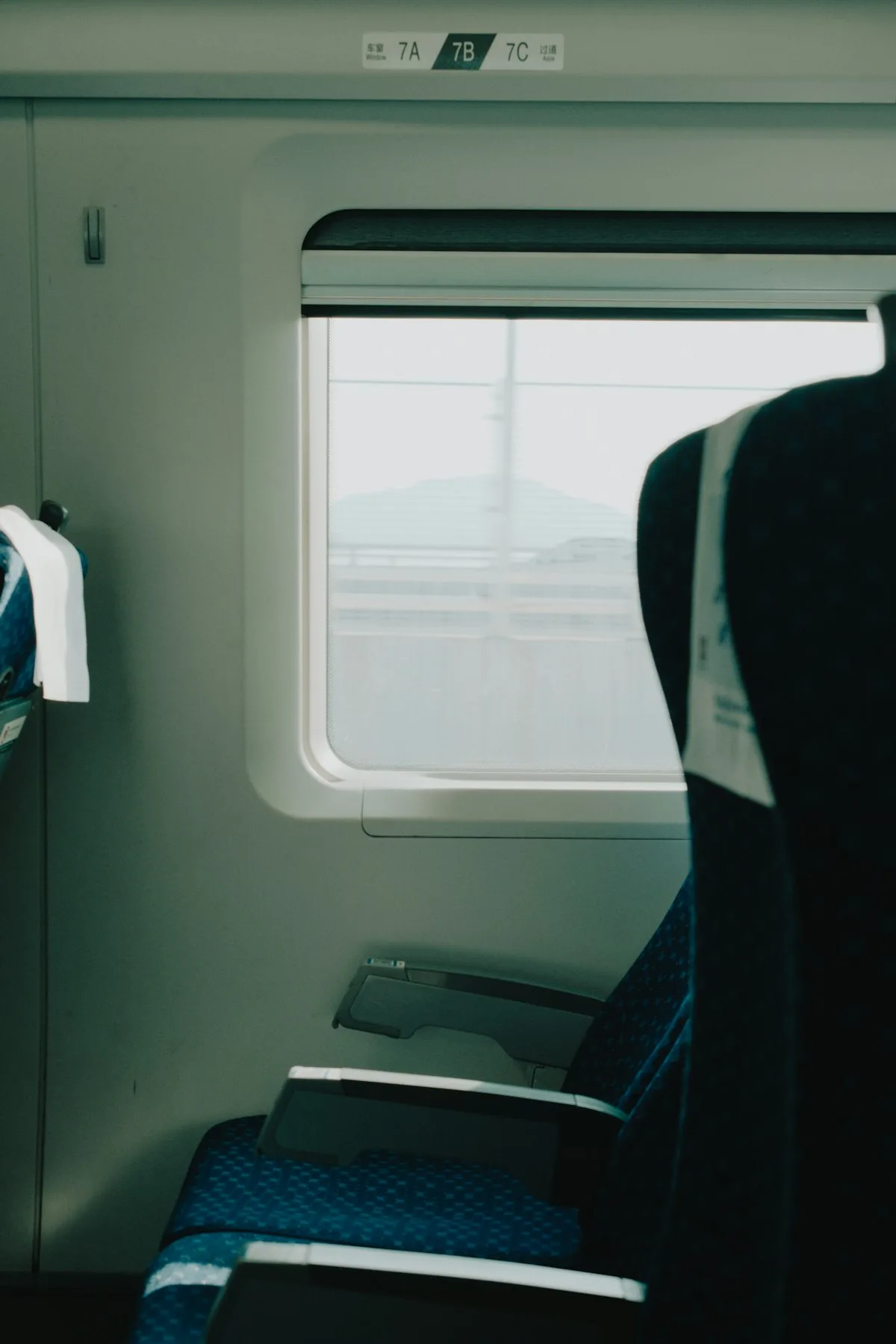 Interior de segunda clase en tren de alta velocidad chino: distribución 3+2 con buen espacio para piernas, enchufes y mesas plegables