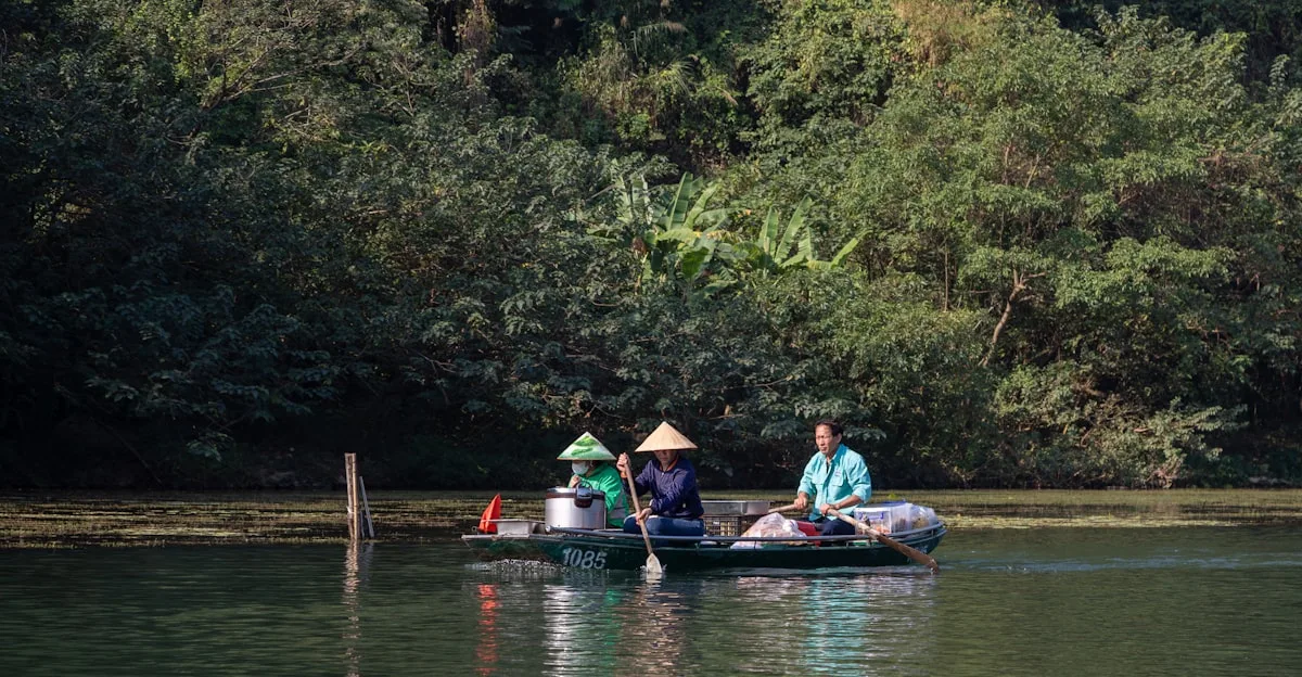 Travelers in conical hats sharing a small boat on the Li River, the same stretch of karst-lined water that appears on the ¥20 note