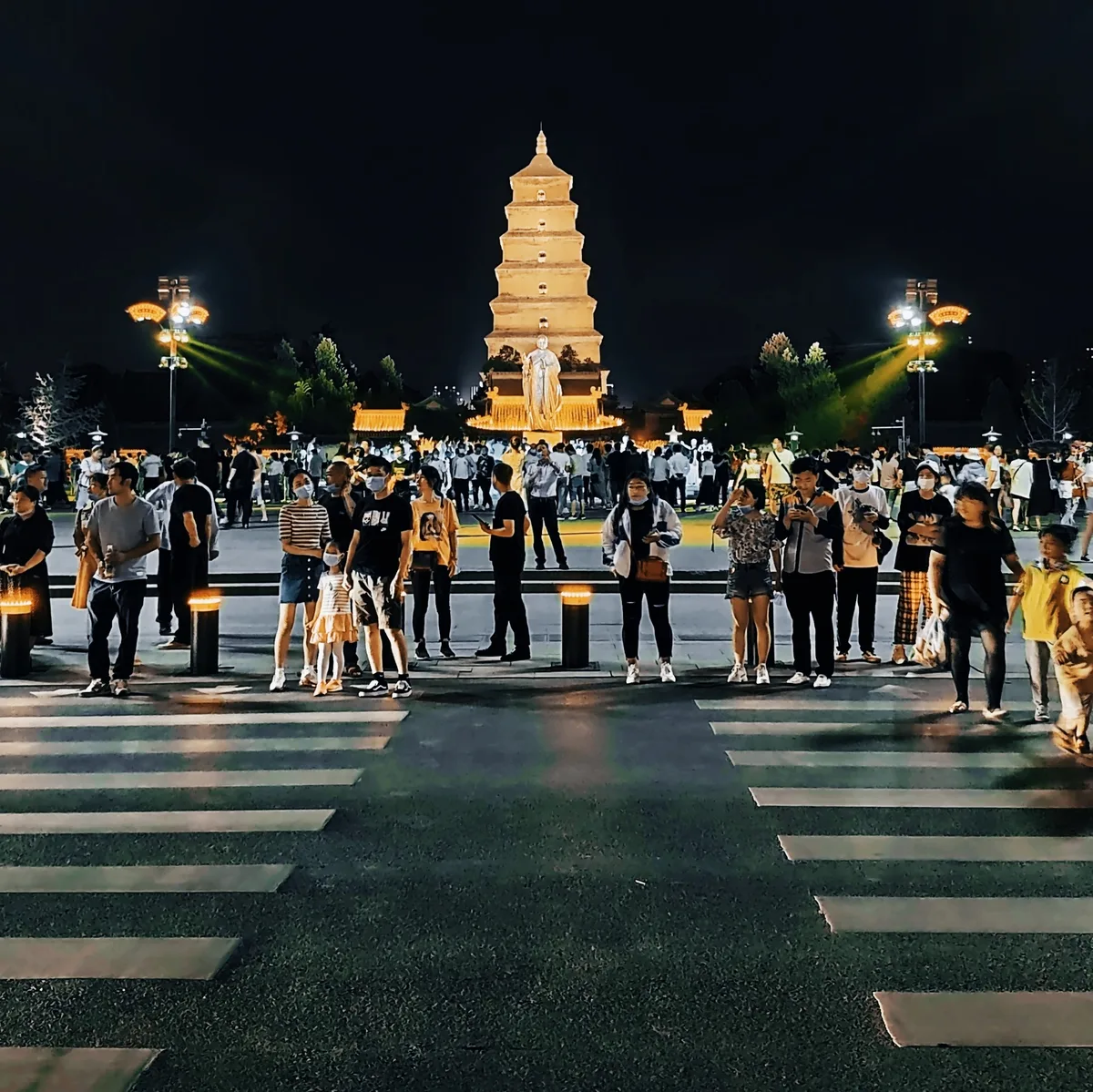 Une foule dense attendant à un passage piéton devant la Grande Pagode de l'Oie sauvage illuminée à Xi'an, la pagode et sa statue éclairées sur un ciel noir (Photo: Qianeal via Wikimedia Commons)