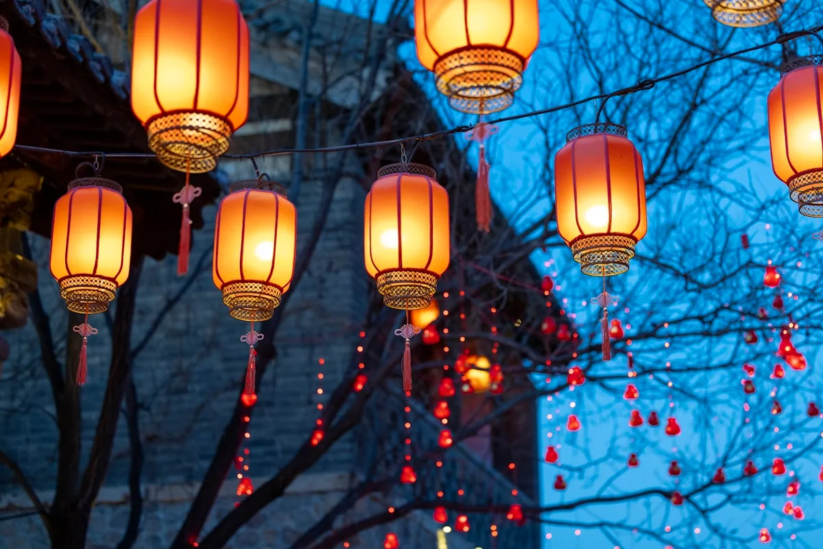 Traditional red Chinese lanterns strung up against a brick wall at night, the festival decoration seen across parks and streets during Mid-Autumn
