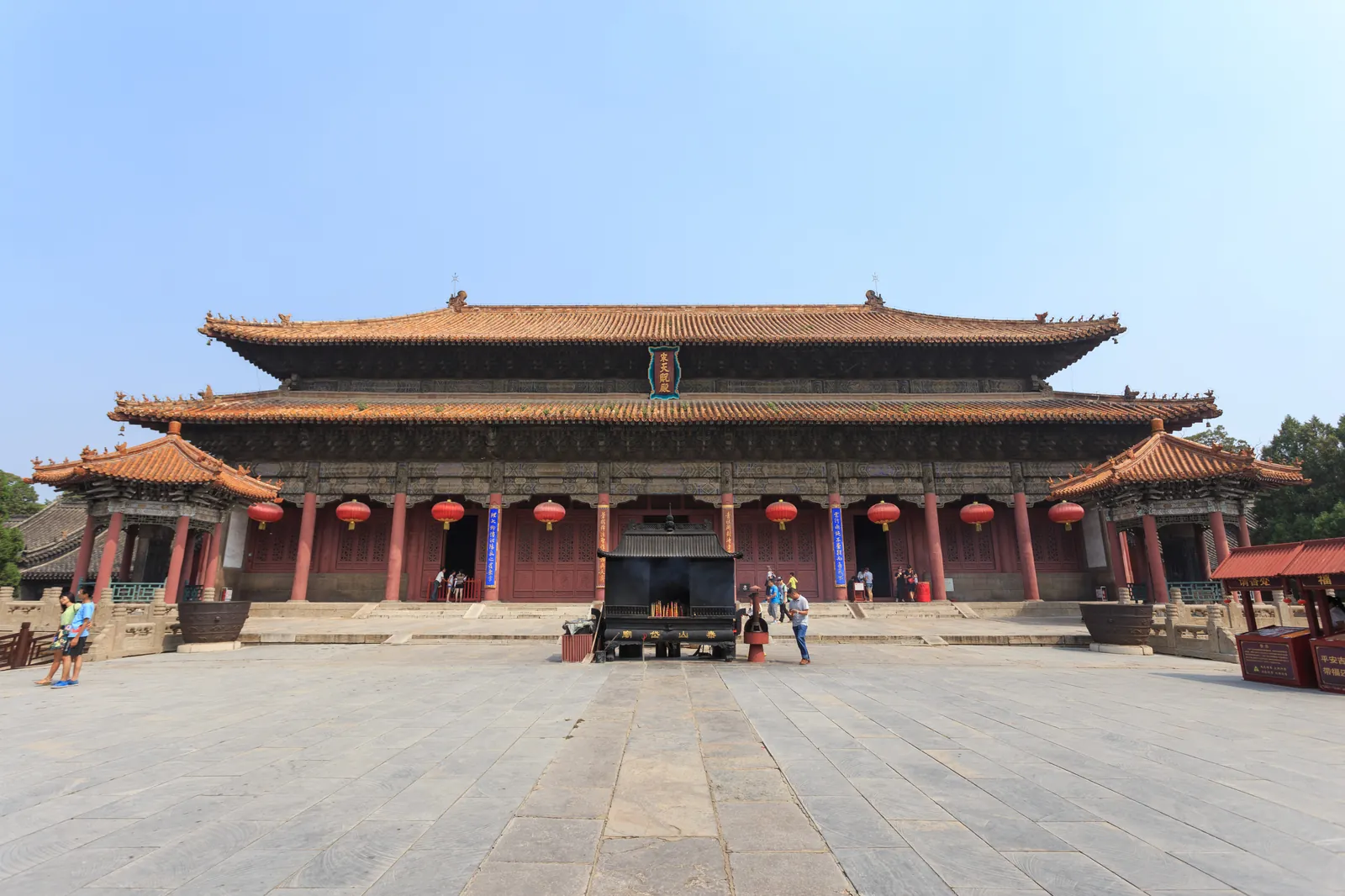 Le hall principal du temple Dai à Tai'an, un large bâtiment de bois rouge et gris sur une plateforme de pierre surélevée sous un ciel dégagé (Photo : Zhangzhugang via Wikimedia Commons)