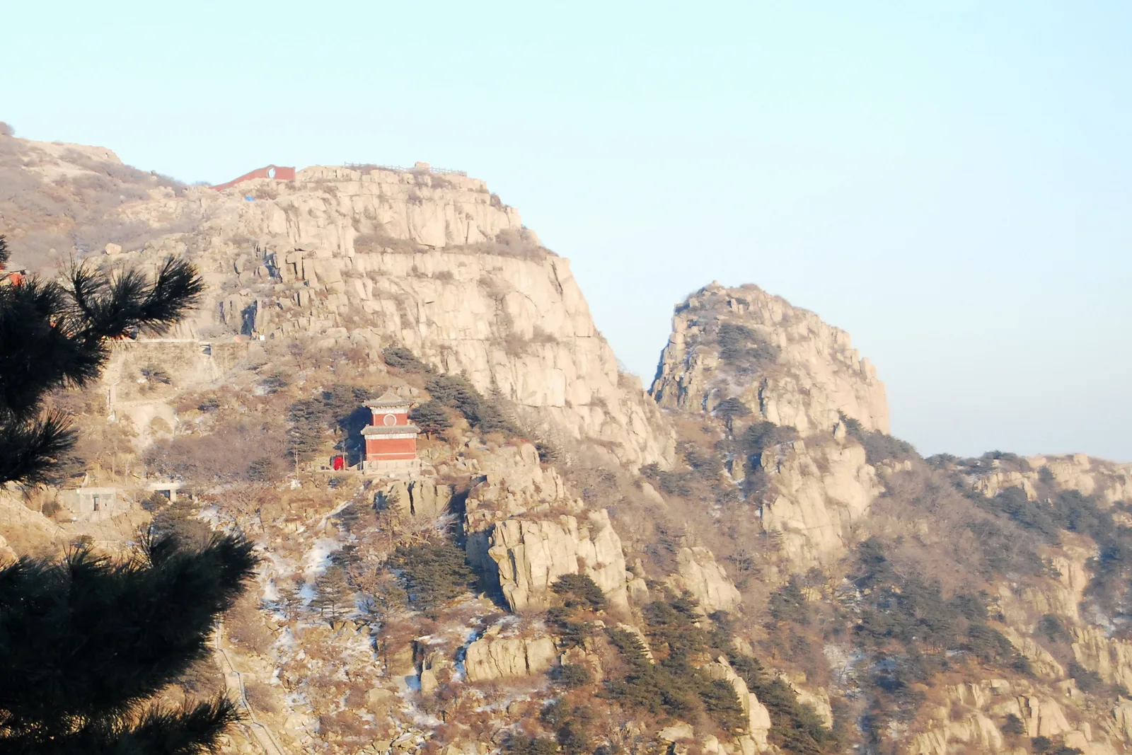 The stone path dropping away from the red gatehouse of Nantianmen across the bare granite slopes of Mount Tai in winter (Photo: shizhao via Wikimedia Commons)