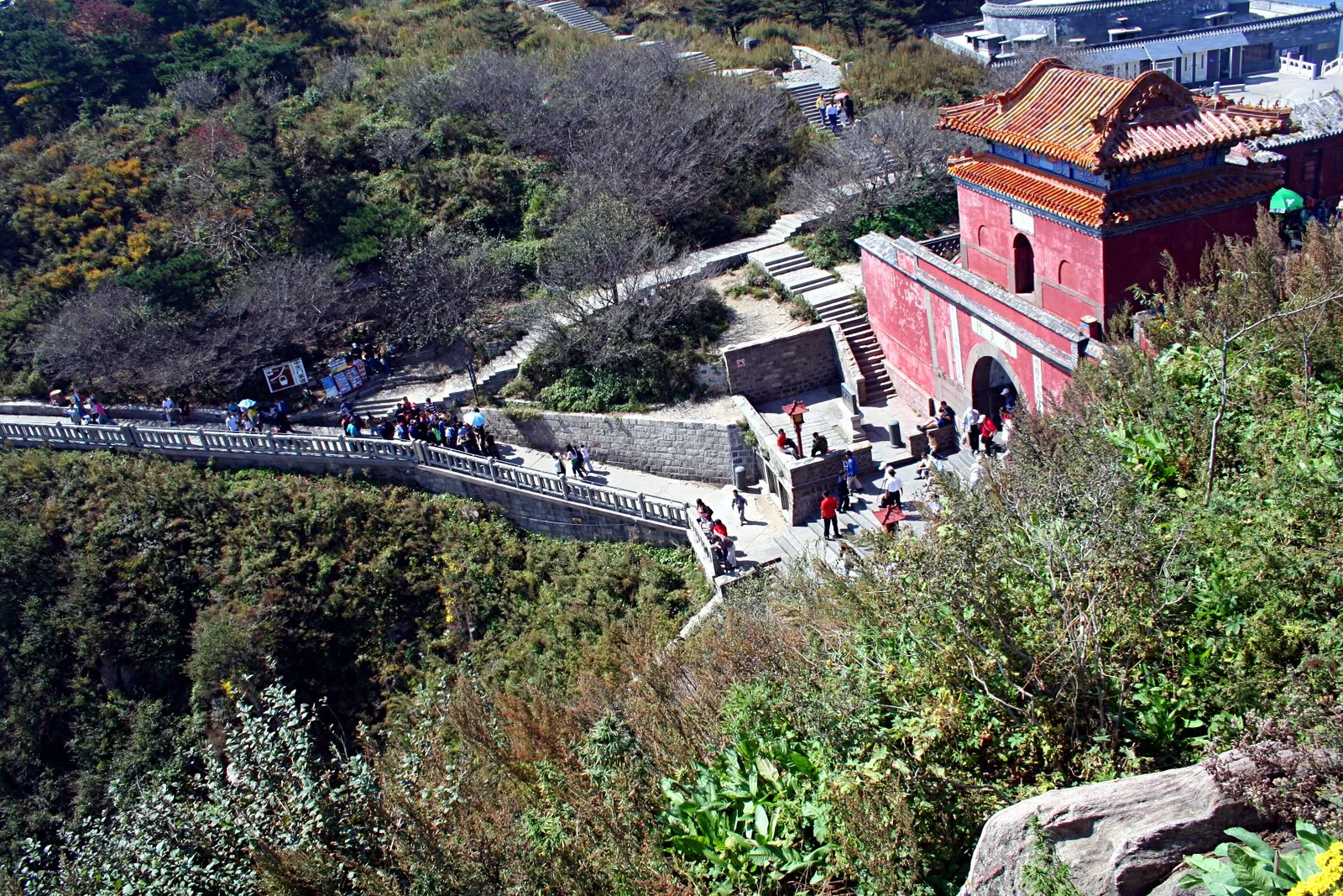 People filing along the stone walkway and steps below the red gatehouse of Nantianmen on Mount Tai, with crowds spread along the path in autumn (Photo: Rolf Müller via Wikimedia Commons)