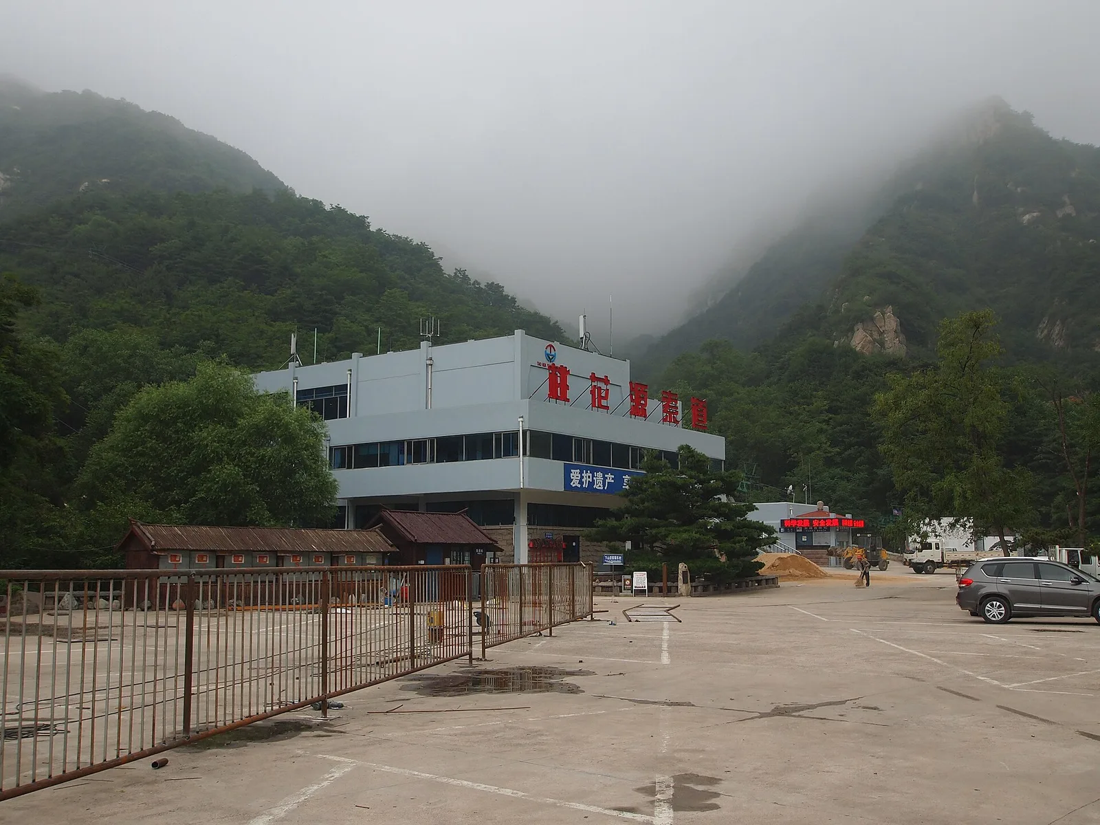 The lower cableway station at Peach Blossom Valley on the west slope of Mount Tai, its red rooftop characters reading Taohuayu cableway, under mist