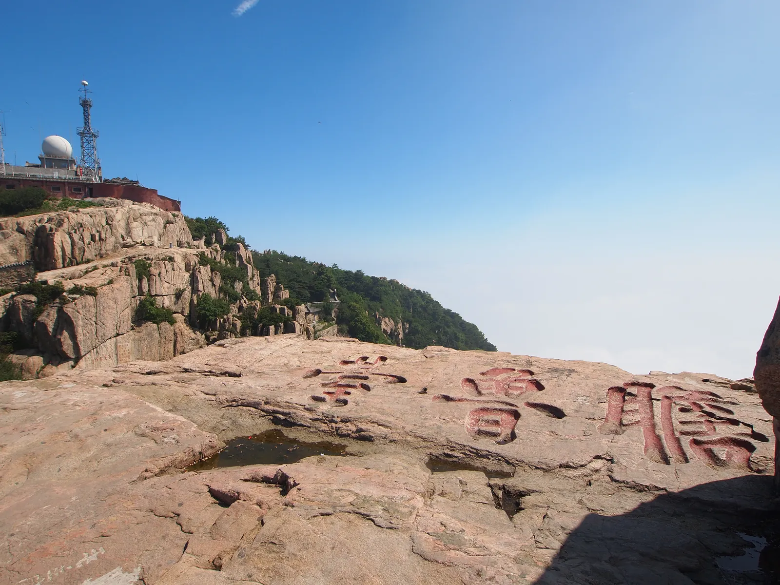 La repisa plana de granito de la plataforma Zhanlu en la cima del monte Tai, con su nombre tallado en grandes caracteres rojos en la roca y la cúpula del observatorio en la cresta detrás (Foto: rheins vía Wikimedia Commons)
