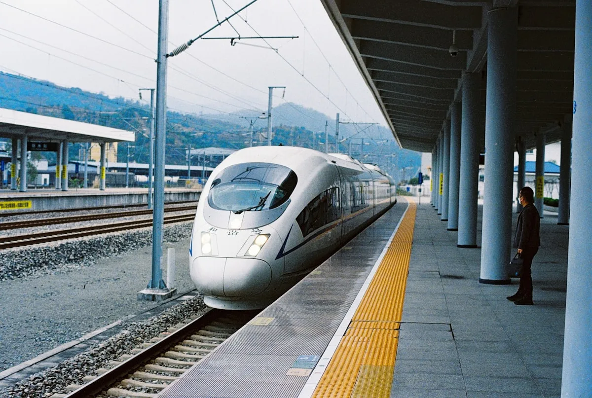A high-speed train waiting at a station platform in a mountainous region of China