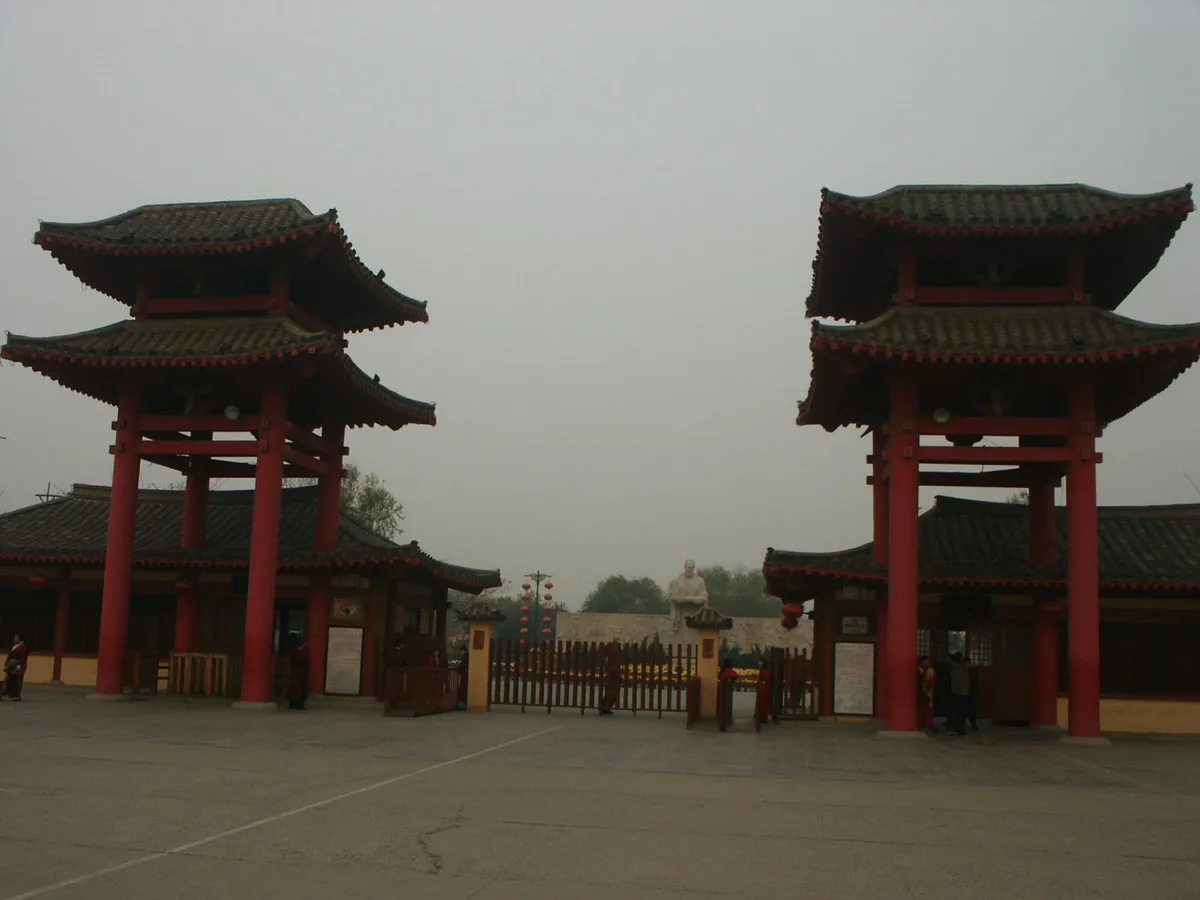 Les deux tours-portes rouges de l'entrée principale du jardin Qingming Shanghe à Kaifeng, avec la statue du peintre Zhang Zeduan visible à travers le portail (Photo: Gary Todd via Wikimedia Commons)