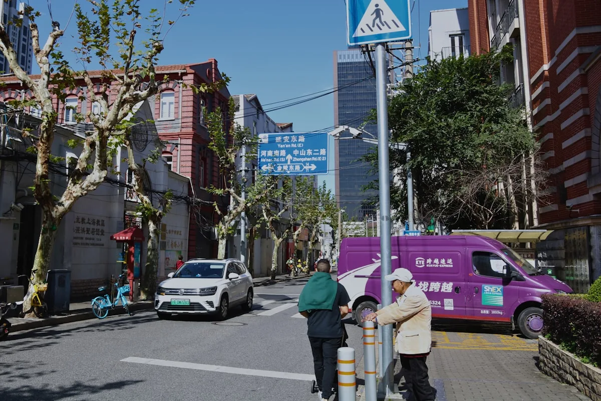 Plane trees shading a residential street in the former French Concession, red-brick buildings and local traffic typical of the Wukang Road area