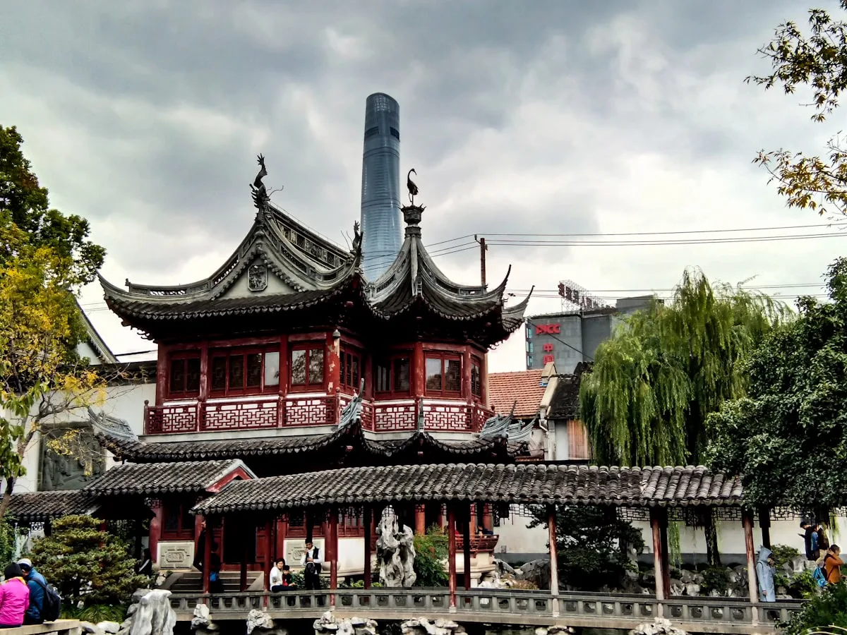 The Nine-Turn Bridge and classical pavilions of Shanghai's Yu Garden, crowded with visitors at the edge of the Old City