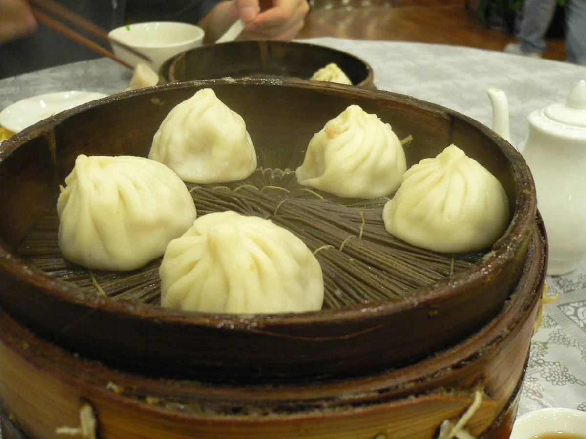 Cinco xiaolongbao en una cesta de bambú sobre una mesa de restaurante (Photo: Matt's Life via Wikimedia Commons)