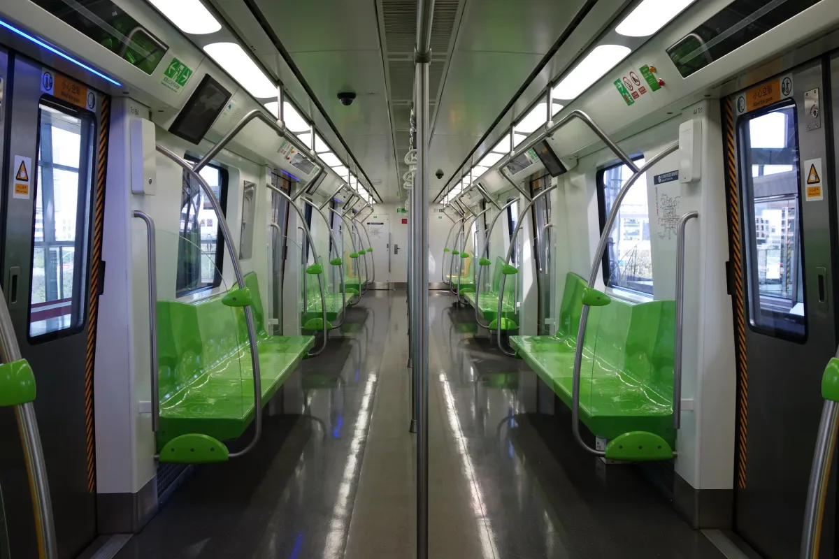 An empty Beijing subway car with rows of green plastic seats and stainless steel handrails (Photo: Tyg728 via Wikimedia Commons)