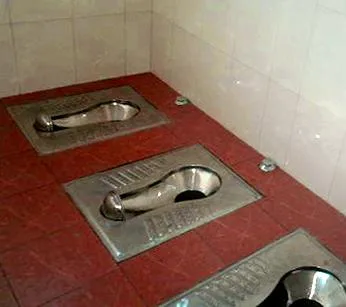 Three squat toilets set into the tiled floor of a public restroom in Beijing (Photo: Marihachi via Wikimedia Commons)
