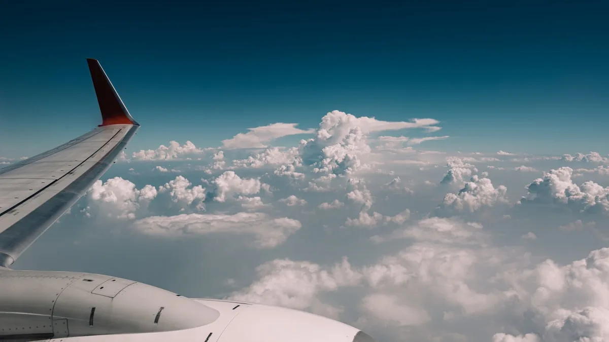 The wing of an airplane in flight above a white layer of clouds, seen from a passenger window